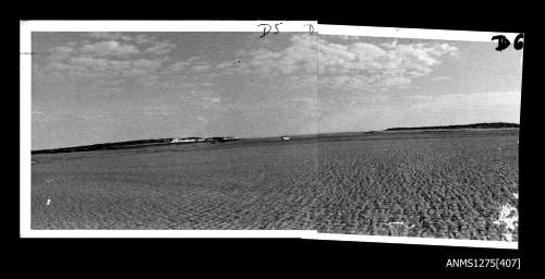 Photograph, composed from two photographs, glued together, of sand or shallow water, with land in the distance