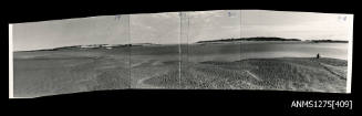 Photograph of beach and ocean, with land in the distance, composed from four photographs glued together