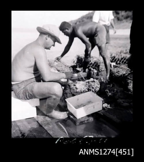 Two men working with pearl shells and pearl cages on Packe Island