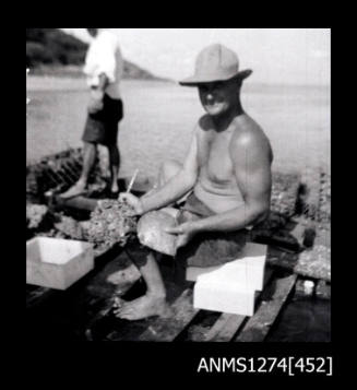 A sitting man, holding two pearl shells on Packe Island