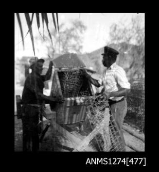 Two men putting pearl cages into the cleaning machine on Packe Island