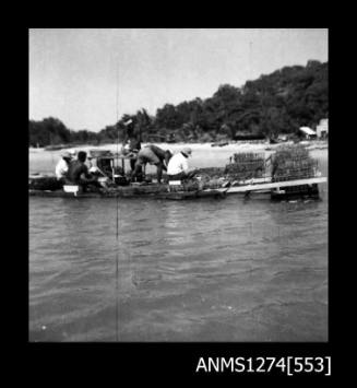 Several people working on a pearl raft, alongside pearl cages, on Packe Island