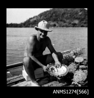 A man, possibly Denis George, holding an open pearl shell, on Packe Island