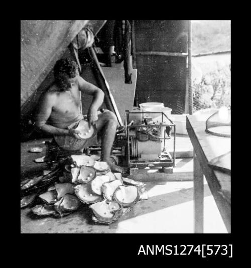 A man sitting, with a pile of pearls shells in front of him, on Packe Island