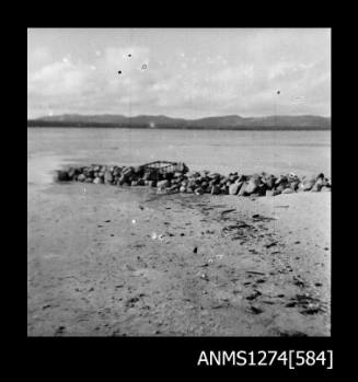 A metal cage sitting on a rock wall on Packe Island