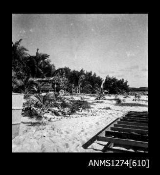 A wooden structure surrounded by palm trees on Packe Island, with a sign saying Warning, keep out, Dingo traps set in Garden and Camp