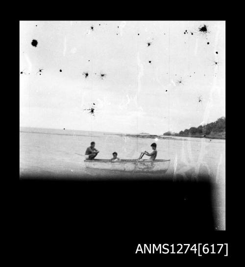 Three people sitting in a boat on Packe Island, near the shoreline