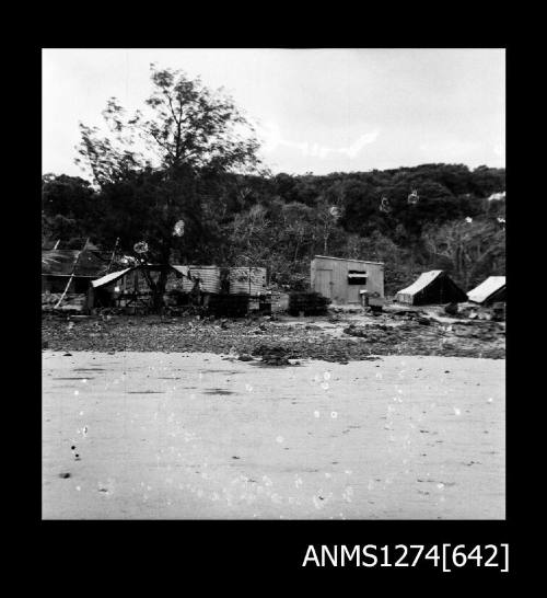 A shed, tents, and a building that is being built on the shoreline on Packe Island