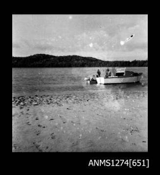 Three people in two boats in the water on Packe Island