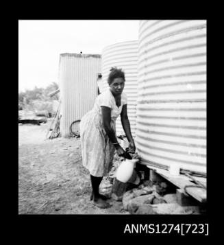 A woman standing next to two large metal cylinders, on Packe Island