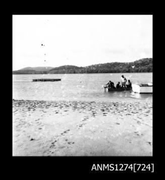 Several people in a boat, near a pearl raft, on Packe Island