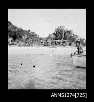 Person sitting at the front of a boat in the water, facing land on Packe Island