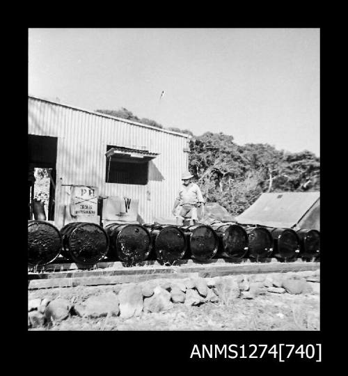 Several metal drums laid out in a line in front of a shed on Packe Island