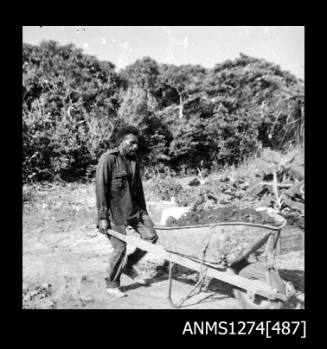 A man pushing a wheelbarrow on Packe Island