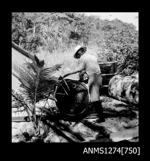 A man rolling [?] a metal drum on Packe Island