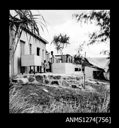 A man and small child standing outside of a house on Packe Island