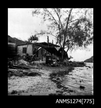 A shed with a shade structure, and people standing out the front, on Packe Island