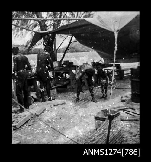 Several people constructing pearl cages under a shade cover on Packe Island