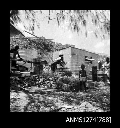 Several people standing in front of a shed, surrounded by wire and other equipment, on Packe Island