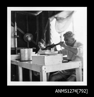 Yurie (or Yulie) George and a man seeding pearls in a shed on Packe Island