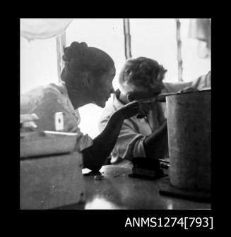 Photograph of of Yurie (or Yulie) George sitting near a man at a work bench, on Packe Island