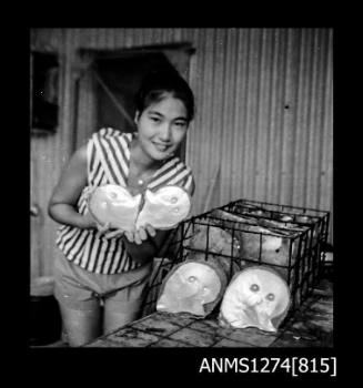 Yurie (or Yulie) George holding two pearl shells, next to a pearl cage with two pearl shells sitting at the front, on Packe Island