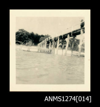 A walking bridge from the beach, and over the water, at Green Island, with a person standing on the bridge