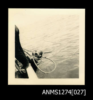 A person over the side of a boat, with a scuba diving helmet on, on Packe Island