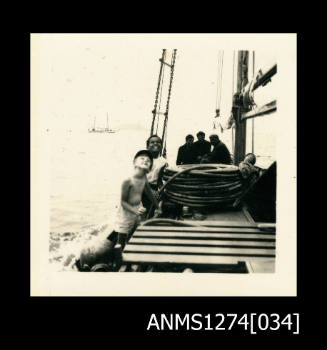 Photograph, of several people in a boat, including the two young children photographed in ANMS1274[033], on Packe Island