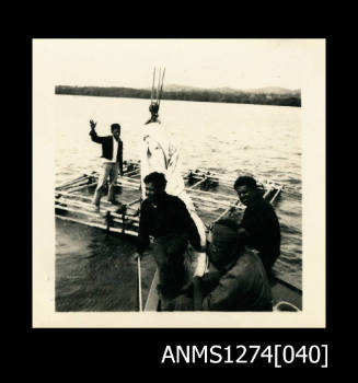 Photograph of four men on, and near, a metal pearl diving structure over the water, on Packe Island