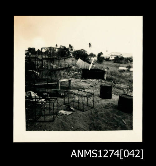 Photograph of land on Packe Island, with several wire pearl cages, drums, etc