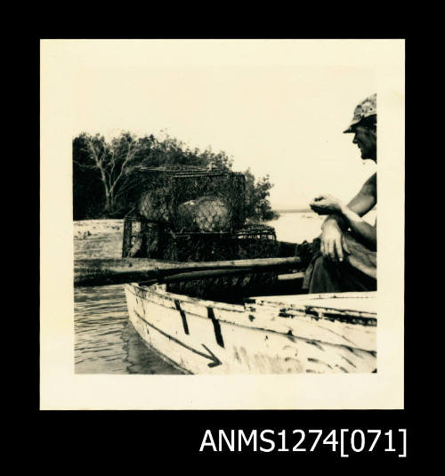 A small boat, with a man sitting in it with wire pearl cages, on Packe Island