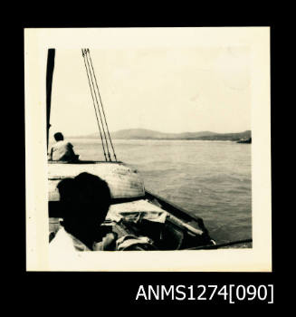 Two people on a boat, with land visible in the background, on Packe Island