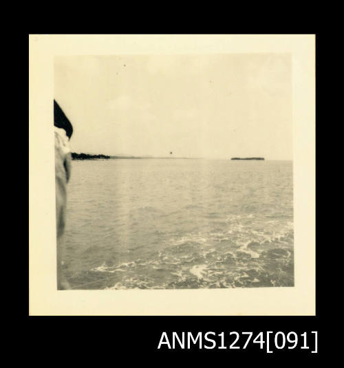 Photograph of ocean and land, taken from the back of a boat, on Packe Island