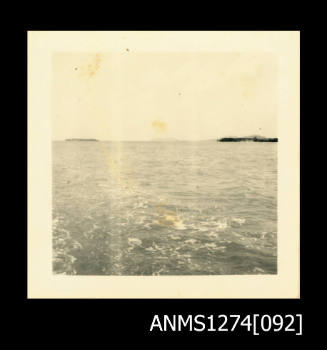 Photograph of ocean and land, taken from the back of a boat, on Packe Island