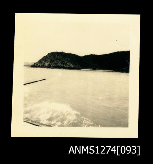 Photograph of ocean and land, taken from a boat, on Packe Island