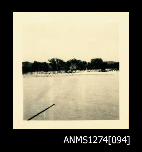 Photograph of ocean, land and beach, taken from a boat, on Packe Island