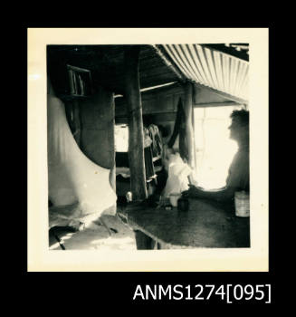A man sitting at a desk, inside of a room, or shed, on Packe Island