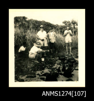 Photograph of five men opening pearl shells in sand, on Packe Island