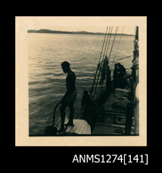 Photograph of several men looking over the side of a boat at the water, at Packe Island