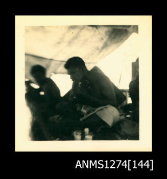 Two men, sitting under a shade cloth on a boat, on Packe Island