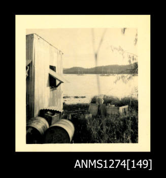 The outside of a tin shed, with a view of the water, at Packe Island