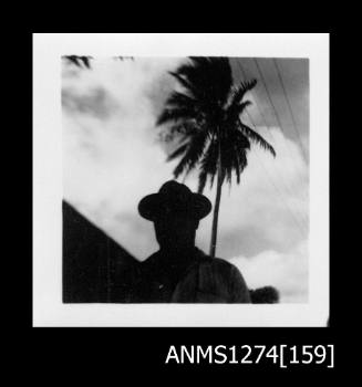 A man, standing in front of a palm tree, on Packe Island