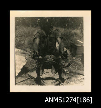 A man holding an outstretched crab in front of him, on Packe Island