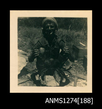 A man holding an outstretched crab in front of him, on Packe Island