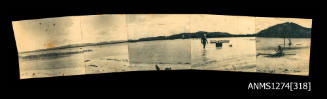 Photograph of a beach, land, and two men in the water, composed from five small Photographs, which have been glued together to create a continuous view of the beach