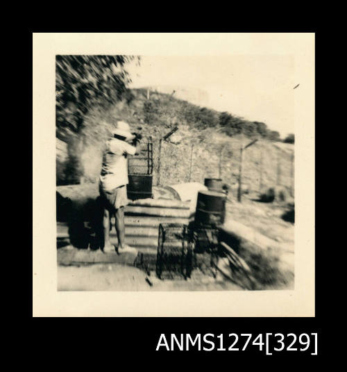 Photograph of equipment, such as pearl cages and metal drums, and Denis George, on Thursday Island