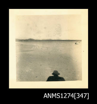 A beach, with a mans shadow, on Packe Island