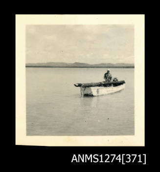 A man standing in a boat with a mangrove log, on Packe Island