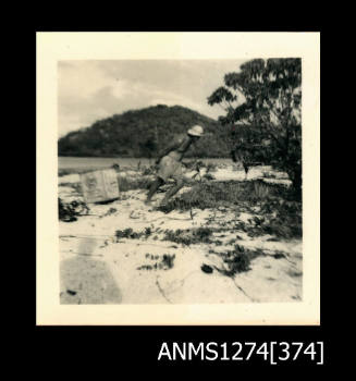 A man on a beach, putting a wooden box, on Packe Island